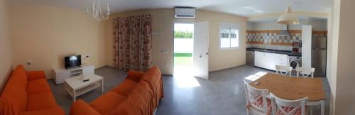 a living room with an orange couch and a kitchen at Casa los Naranjos 1 in Conil de la Frontera