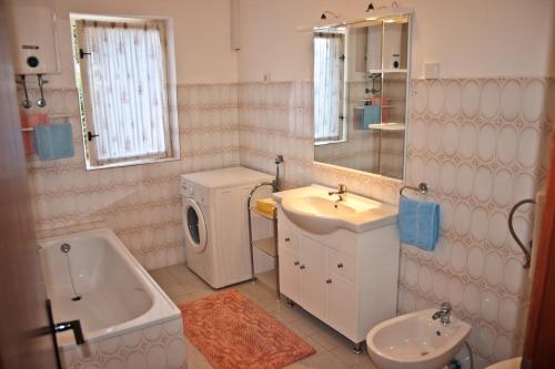 a bathroom with a sink and a washing machine at Apartments Simuni 66 in Šimuni