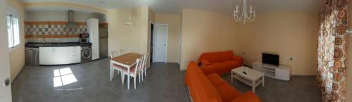 a living room with an orange couch and a table at Casa los Naranjos 1 in Conil de la Frontera