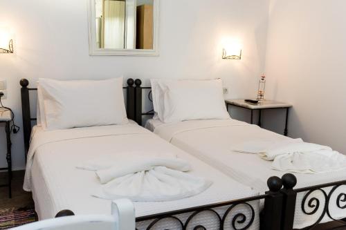 two beds in a bedroom with white sheets and a mirror at Natura Stone House in Sissi