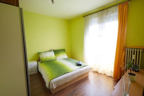 ペーチにあるEgyetemváros - A. apartmanの緑のベッドルーム(ベッド1台、窓付)