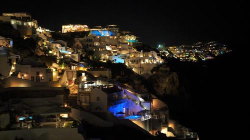 a group of white buildings on a hill at night at Aqua & Terra Traditional Cave Houses in Oia
