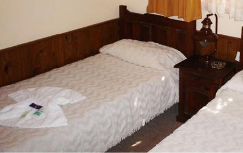 een slaapkamer met twee bedden en een houten hoofdeinde bij Hosteria Actinia in Villa Gesell