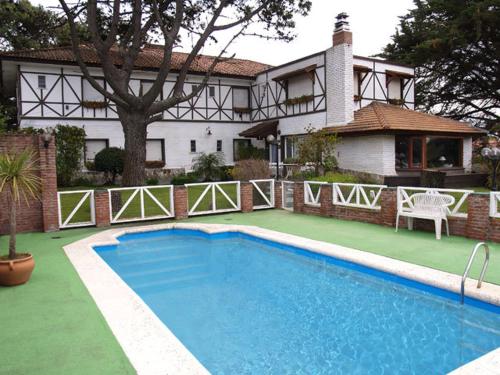 una casa con piscina frente a una casa en Hostería Actinia en Villa Gesell