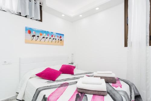 Un dormitorio con una cama con almohadas rosas y una pintura en 241 Quiet Bungalow with terrace, en Playa de las Américas