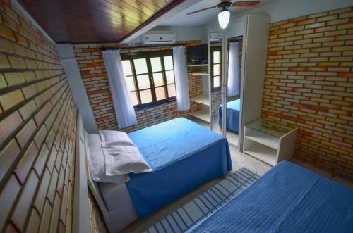 a bedroom with a blue bed and a brick wall at Residencial Costa Mar in Bombinhas