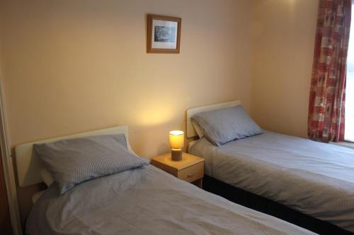 1 dormitorio con 2 camas y mesita de noche con lámpara en Ishara Apartment, en Weymouth