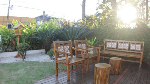 two chairs and a bench on a wooden deck at Atena Praia Hotel in Boicucanga