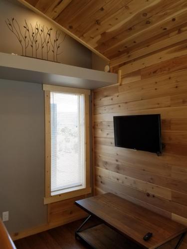 a living room with a flat screen tv on a wooden wall at Escalante Cabins & RV Park in Escalante
