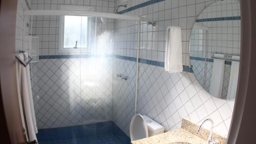 a bathroom with a shower and a toilet and a sink at Atena Praia Hotel in Boicucanga