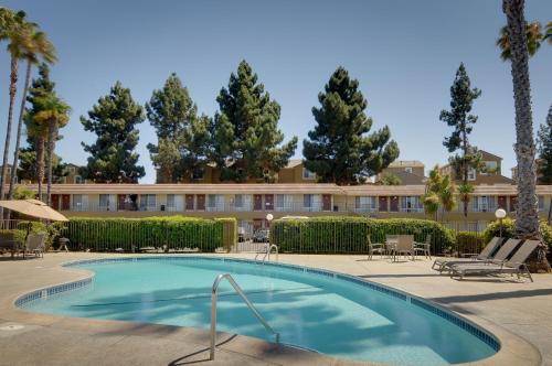 a swimming pool in front of a hotel with palm trees at Rodeway Inn in Santa Clara