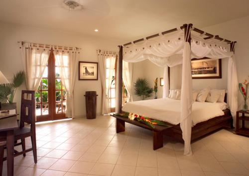Antigua Yacht Club Marina Resort في إنغليش هاربور تاون: غرفة نوم مع سرير المظلة وطاولة