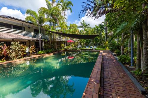 - une piscine en face d'une maison avec des palmiers dans l'établissement King Reef Resort, à Kurrimine Beach