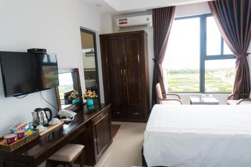 a hotel room with a bed and a desk with a television at Aries Hotel in Tuy Hoa