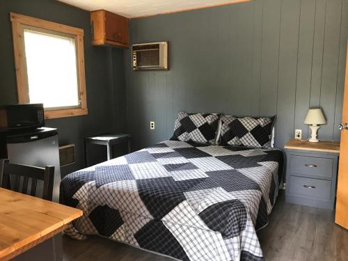 a bedroom with a bed with a checkered blanket at Jasper Way Inn Resort & Campground in Clearwater