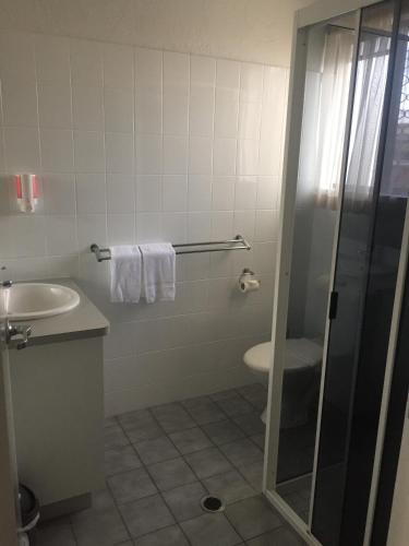 a bathroom with a shower and a sink and a toilet at Bundaberg Spanish Motor Inn in Bundaberg