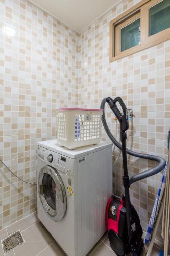 a washing machine in the corner of a bathroom at Home Fourest Residence Hotel Okpo in Geoje 