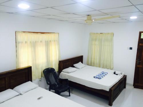 ein Schlafzimmer mit 2 Betten und einem Stuhl darin in der Unterkunft Bindu Homestay in Wellawaya