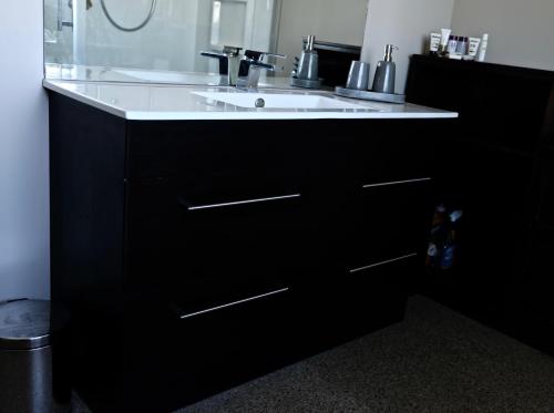 a bathroom with a white sink and a black cabinet at Kahu Farm Apartment in Matakana