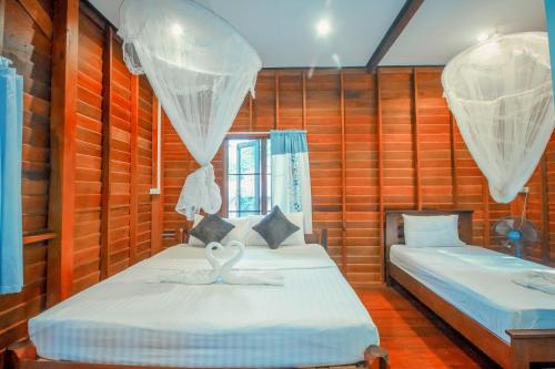 two beds in a room with wooden walls at Khao Sok Palmview Resort in Khao Sok