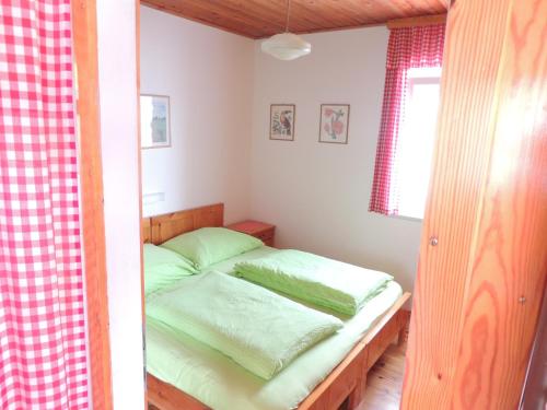 ein kleines Schlafzimmer mit einem Bett mit grüner Bettwäsche in der Unterkunft Ferienhäuser Zak in Sankt Kanzian am Klopeiner See
