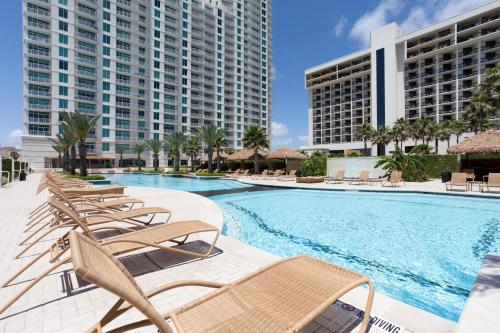 a swimming pool with chaise lounge chairs and buildings at Sapphire in South Padre Island