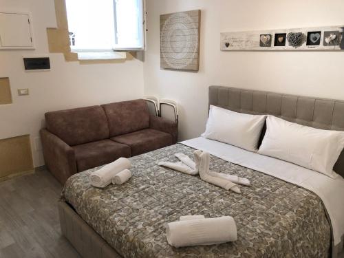 una camera con un letto, un divano e due asciugamani di Appartamento Ortigia a Siracusa