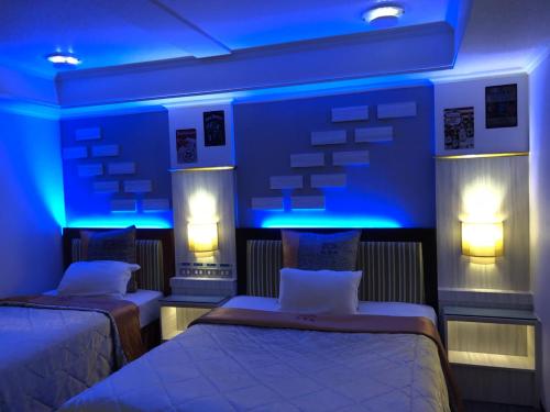 two beds in a room with blue lights at Beverly Commercial Motel in Luzhu
