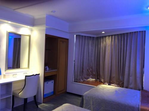 a bedroom with a bed and a desk and a mirror at Beverly Commercial Motel in Luzhu