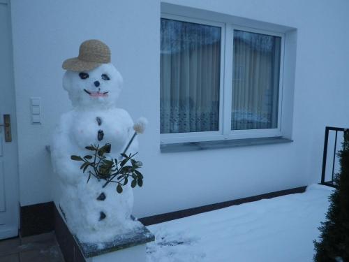 a snowman with a hat and a vase with a flower at Ferienwohnungen Stranddistel - Apartments von 30 bis 75 qm in Zinnowitz