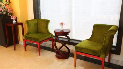 three green chairs and a table with a vase on it at Grand Serenaa Hotel & Resorts, Auroville in Auroville