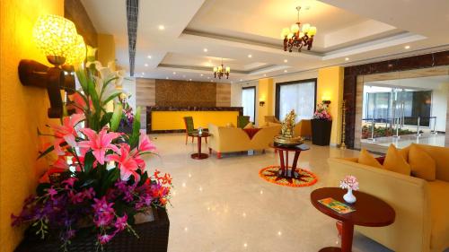 a lobby with couches and flowers in a building at Grand Serenaa Hotel & Resorts, Auroville in Auroville