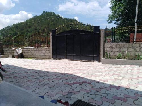 a driveway with a black gate and a stone patio at Panauti Homestay in Panauti
