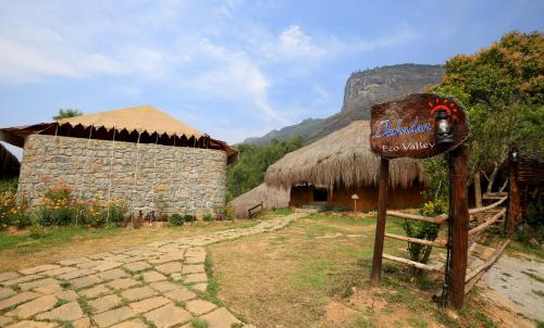 a sign in front of a building with a mountain at Deshadan Eco Valley Resort - An Eco friendly Mud House in Kanthalloor