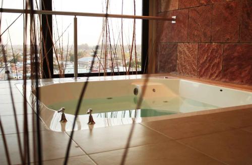 a bath tub in a room with a large window at Condado Hotel Casino Goya in Goya