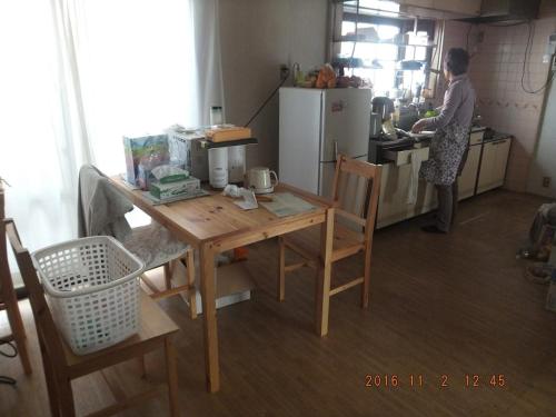 a woman standing in a kitchen with a wooden table at Hirakata-park Guesthouse in Hirakata