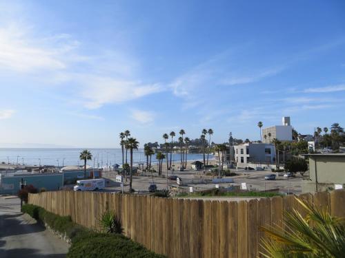 a fence next to a beach with palm trees and the ocean at Beach Street Inn and Suites in Santa Cruz