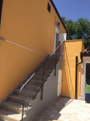 a person looking out the window of a yellow building with stairs at Il Daviduccio Suite in Siracusa