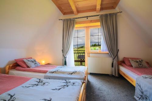 two beds in a room with a window at Folk Resort Domki i Apartamenty in Murzasichle