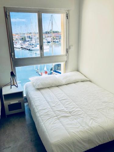 a bedroom with a bed and a window with a marina at 3 plan des boucaniers in Cap d'Agde