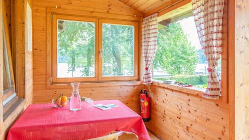 a red table in a room with two windows at Ferienwohnungen Lipnik am See in Sankt Kanzian