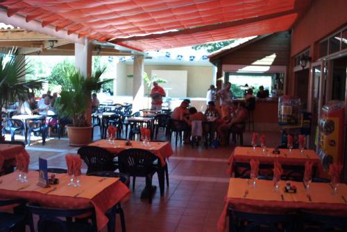 a restaurant with red tables and chairs and people in the background at Vias Plage Camping Salisses in Vias