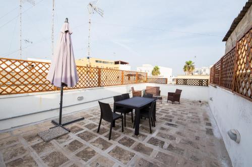 eine Terrasse mit einem Tisch und einem Sonnenschirm auf dem Dach in der Unterkunft Casa Vacanze Capitano in Porto Cesareo