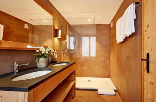 a bathroom with two sinks and a mirror and a shower at Hotel Sanetsch in Gsteig