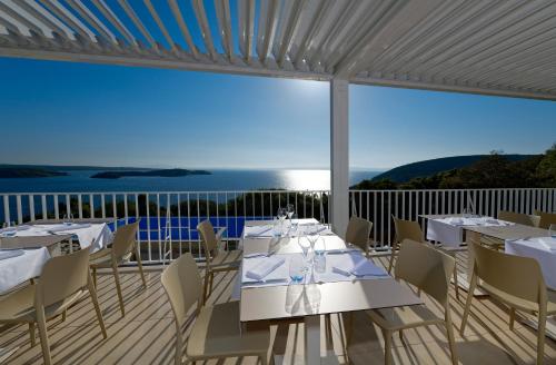 a restaurant with white tables and chairs on a balcony at Zlatni Zalaz,Apartments,Supetarska Draga in Supetarska Draga