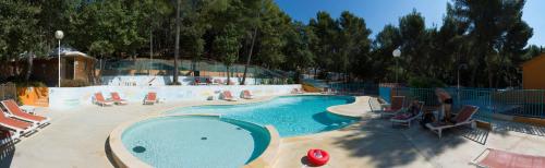 une grande piscine avec des chaises et un bassin de natation dans l'établissement Camping les Playes, à Six-Fours-les-Plages