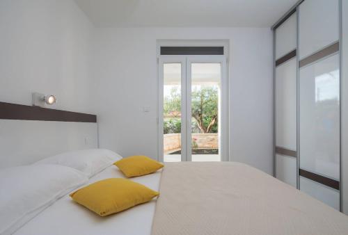 a bedroom with a bed with two yellow pillows on it at Apartmani Kos in Supetar