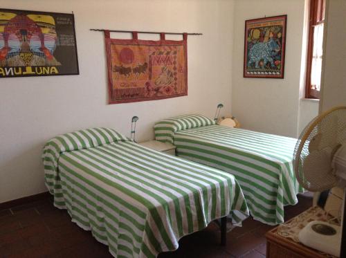 Habitación con 2 camas con sábanas de rayas verdes y blancas en La casa di Angelo e Gladys, en Bella Farnia