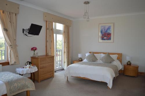 a bedroom with two beds and a tv on the wall at Strathview Lodge in Dornoch