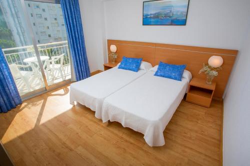 sypialnia z łóżkiem z niebieskimi poduszkami i balkonem w obiekcie Gandia Playa w mieście Gandía